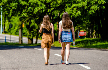 Two girlfriends walk along a path in the Park
