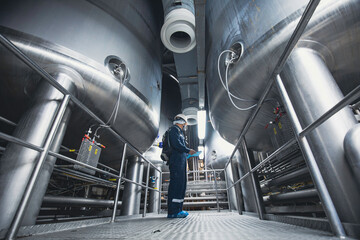 Male work inspection process stainless steel tanks and pipe with pressure meter in equipment tank facility for milk cellar at the with vertical stainless mixing tank