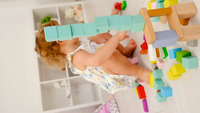 The child plays in the children's room with a wooden constructor. Selective focus.