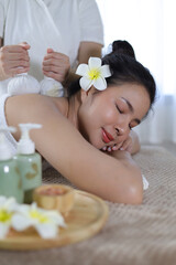 Obraz na płótnie Canvas Woman Enjoying Herbal Massage. Relaxed Asian girl sleeping with eyes closed receiving traditional Thai herbal massage with fragrant bags. Body beauty treatment, relaxation and wellness.