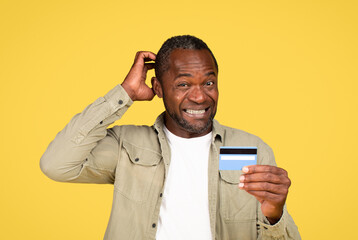 Confused mature black male in casual scratching head, thinking, show credit card