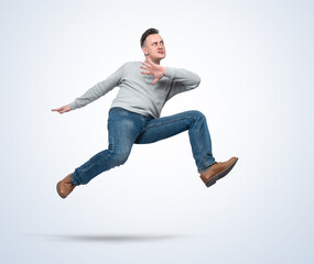 Man in casual clothes runs jumping over an obstacle on a light background