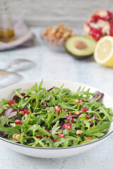 A plate with green rocket salad with pomegranate	