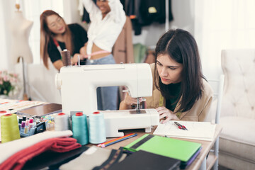 Happy beautiful woman fashion designer clothes working with sewing in own dressmaking studio or boutique	