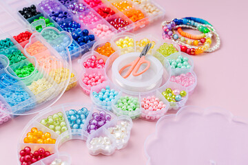 Kids handmade beaded jewelry and different multi-colored beads for children's needlework and crafts in boxes. DIY art activity for kids. Motor skills, creativity and  hobby.