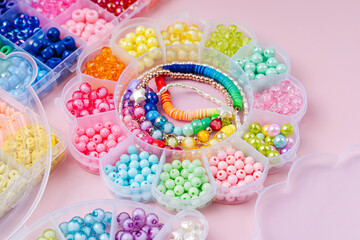 Kids handmade beaded jewelry and different multi-colored beads for children's needlework and crafts in boxes. DIY art activity for kids. Motor skills, creativity and  hobby.