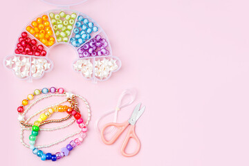Kids handmade beaded jewelry and different multi-colored beads for children's needlework and crafts in boxes. DIY art activity for kids. Motor skills, creativity and  hobby.