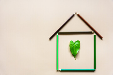 Ein Haus aus Buntstiften mit einem grünen Herzblatt in der Mitte. Umwelt.
