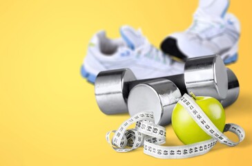 Fitness concept. Dumbbells, sports shoes and apple on desk