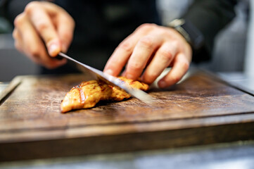 chef is cutting the chicken fillet in a restaurant kitchen