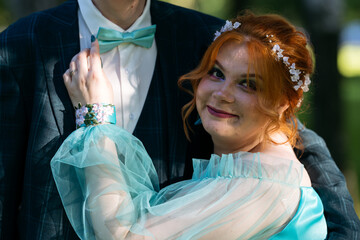 Young redhead bride in blue dress touching groom's bow-tie. Candid photo of young couple of newlyweds. Wedding or prom photo. © Maria