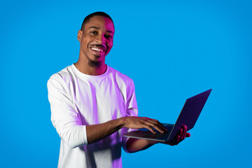 Positive african american man typing on laptop keyboard