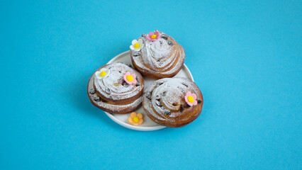 Easter eggs and decor on fresh buns with spirals with white icing sugar.