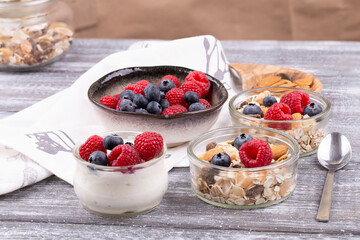 Close-up of granola with nuts, raspberries and blueberries, yogurt on a gray whitewashed rustic table, copy space. healthy breakfast