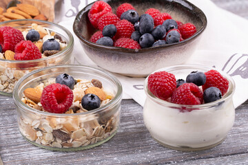 Close-up of granola with nuts, raspberries and blueberries, yogurt on a gray whitewashed rustic table, copy space. healthy breakfast
