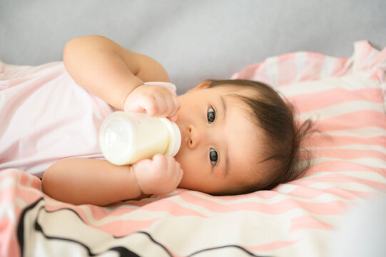 A baby girl is drinking milk bottle, family, child, childhood and parenthood concept