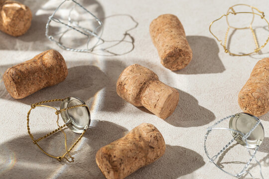 Creative composition made of champagne corks on beige sunlit background with shadow. Bottle caps from sparkling wine and metal wire muselet. Summer party drink concept - Powered by Adobe
