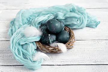 Eggs in a decorative white nest are painted for Easter celebration. Festive decor for breakfast