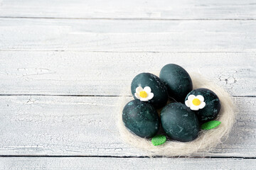 Eggs in a decorative white nest are painted for Easter celebration. Festive decor for breakfast