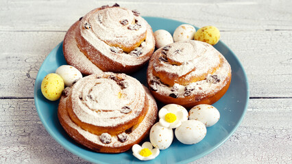 Delicious fresh pastries with icing sugar on a blue plate with chocolate sweet eggs for Easter gift