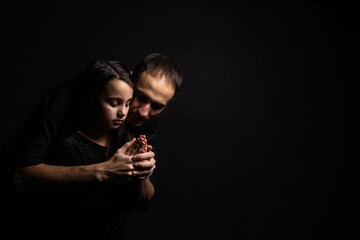 Young father and daughter praying with hands together with hope expression on face very emotional...