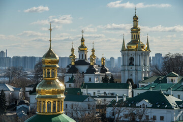 Fototapeta na wymiar Panoramic view of Kyiv Pechersk Lavra churches, the Dnieper river and high buildings in Kyiv, Ukraine. February 2023