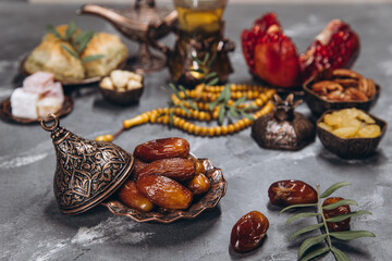 Ramadan table, dates on the background of traditional dishes with other meal, dried fruits, fresh garnet, tea.