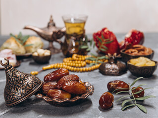 Ramadan table, dates on the background of traditional dishes with other meal, dried fruits, fresh garnet, tea.