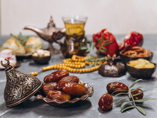 Ramadan table, dates on the background of traditional dishes with other meal, dried fruits, fresh garnet, tea.