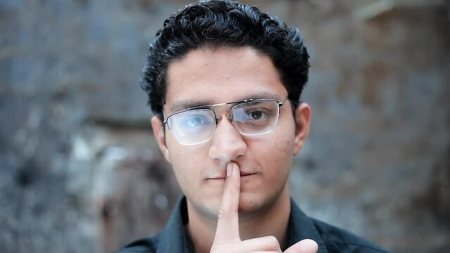 Portrait shot of a male putting finger on his lips. Hd footage 24FPS.  Man making expressions.