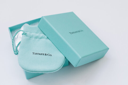 Tiffany branded box with a gift, packed into a cloth bag, on a white background.