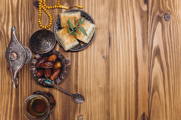 Ramadan concept, cup of tea, plate of sweet dates and baklava, copy space, top view
