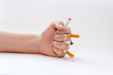 Beautiful female hand breaks cigarettes, clenching her hand into a fist