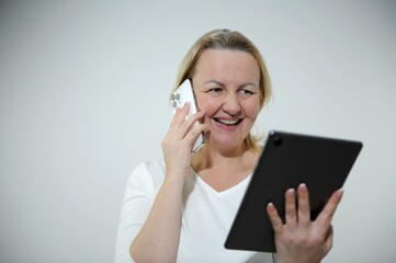 a woman smiling looking at a tablet and talking on the phone good news great prices look for good investments work communication with loved ones a gift a nice message came white background