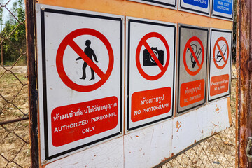 Various type of safety PPE requuired symbol icons in English and Thai languege which are installed on the front gate of unsafe workplace entrance way. Sign for the industrial working.