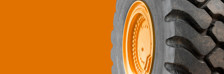 New large tire of an heavy industrial machinery with a bolted yellow wheel rim - image with copy...