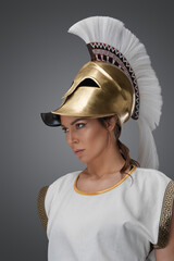 Plakat Portrait of greek soldier woman dressed in ancient armor against grey background.