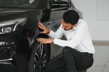 Fototapeta na wymiar A young Indian man chooses a new car at a car dealership