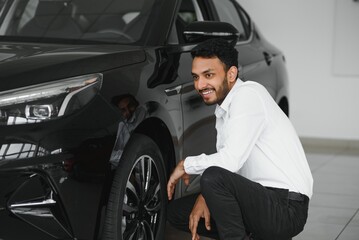 Obraz na płótnie Canvas happy indian man buy new biodiesel eco automobile in lux showroom.