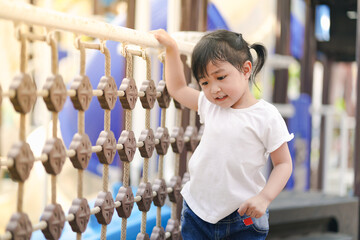 Adorable little girl having fun in the outdoor playground.