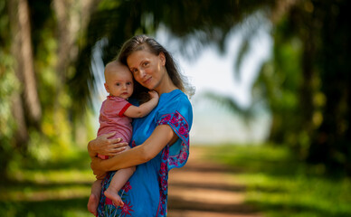 Mother with baby between palm trees