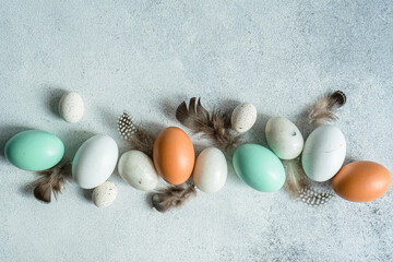 Overhead view of an Easter display of assorted eggs with quail feathers on a table