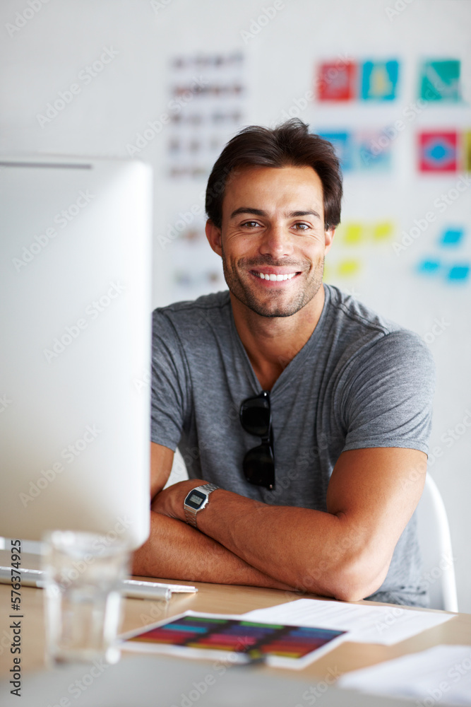 Poster job satisfaction. a handsome young man sitting and smiling in front of his computer.