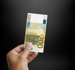 Male hand holding a 200 euro banknote in black background. Europe euro. 3d rendering..