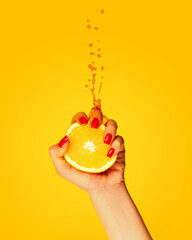 Female hand with bright manicure squeezes half of orange on yellow background. Pop art food photography. Drops of juice fly up