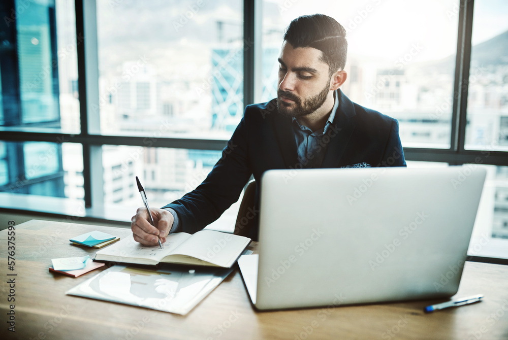 Poster his productivity game is strong. shot of a young businessman writing in a notebook at his desk in a 
