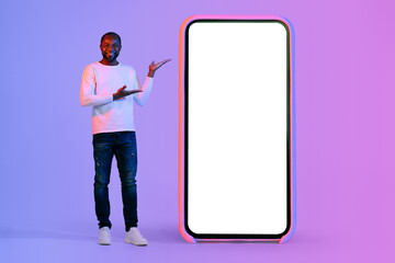 Cheerful black man pointing at big cell phone, mockup