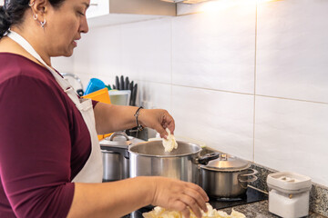50-year-old woman cooking in a pot on an induction stove