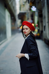 Fashion woman smile with teeth portrait walking tourist in stylish clothes in jacket with red lips walking down narrow city street flying hair, travel, cinematic color, retro vintage style.