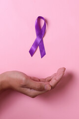 World cancer day, palm hand with purple ribbon on pink background. Healthcare and medical concept....